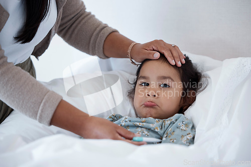 Image of Sick baby in bed with mother hands for child care, support and love. Sad girl at home in winter with a fever, cold or flu and parent, mom or woman help and check temperature with hand on forehead