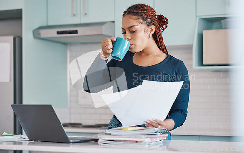 Image of Business woman working remote drinking coffee, analytics or manager with laptop in kitchen, analyzing paperwork and report. Black woman, worker or employee with finance, accounting or tax audit data