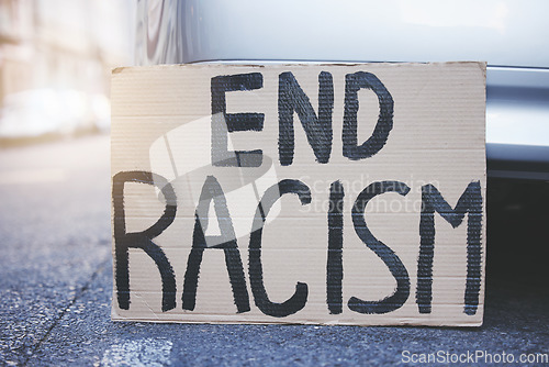 Image of End racism placard, sign and poster for protest in an urban street background for equality, human rights and race problem. Cardboard or billboard advertising fairness, justice and community freedom