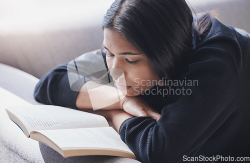Image of Reading, book and serious woman on sofa learning and enjoying hobby, relax and free time at home. Mindful female with novel for knowledge, study and literature or fiction story