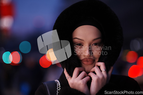 Image of Muslim woman walking on an urban city street on a cold winter night wearing hijab