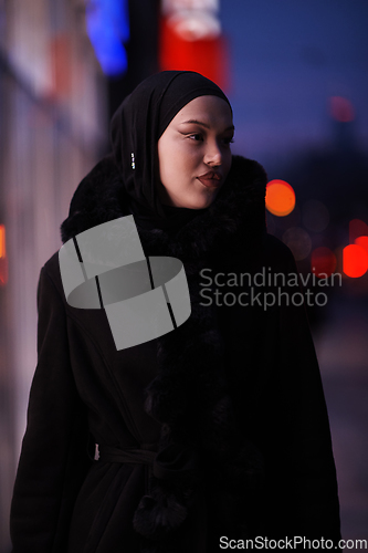 Image of Muslim woman walking on an urban city street on a cold winter night wearing hijab