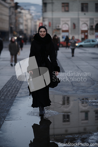 Image of Muslim woman walking on an urban city street on a cold winter night wearing hijab