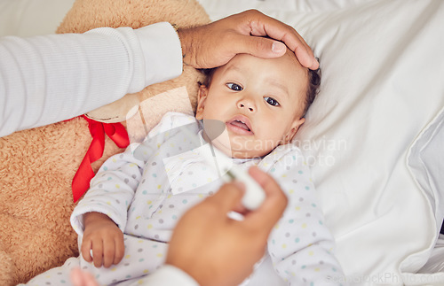 Image of Baby, sick with covid and fever with a thermometer from a parent of an unwell kid in bed of the bedroom of their home. Hand, forehead and healthcare with a child feeling unwell and resting in a house