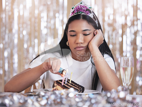 Image of Sad, depression and angry woman at birthday celebration while lighting candle on cake. Lonely, depressed and frustrated female sitting at a party, fail and table with snack, decoration and tiara