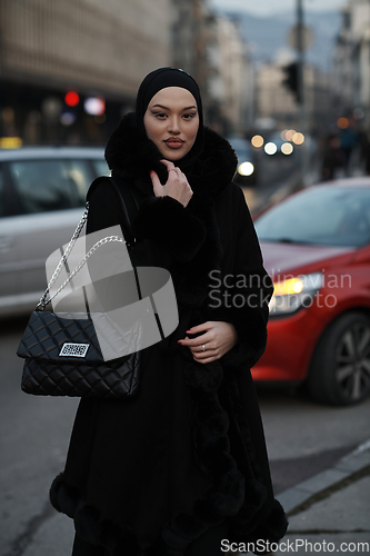 Image of Muslim woman walking on an urban city street on a cold winter night wearing hijab