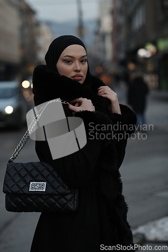 Image of Muslim woman walking on an urban city street on a cold winter night wearing hijab