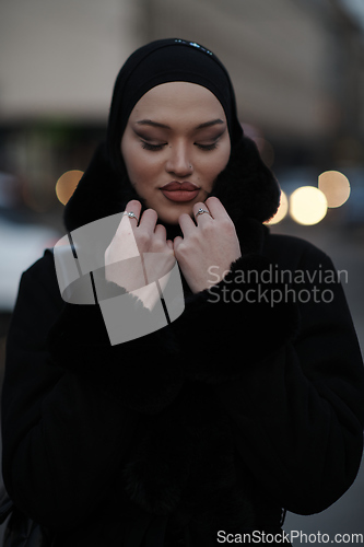 Image of Muslim woman walking on an urban city street on a cold winter night wearing hijab