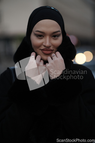 Image of Muslim woman walking on an urban city street on a cold winter night wearing hijab