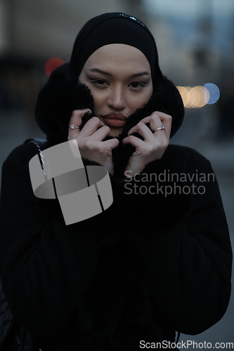 Image of Muslim woman walking on an urban city street on a cold winter night wearing hijab