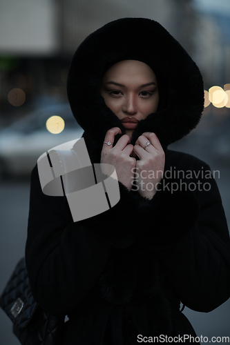Image of Muslim woman walking on an urban city street on a cold winter night wearing hijab