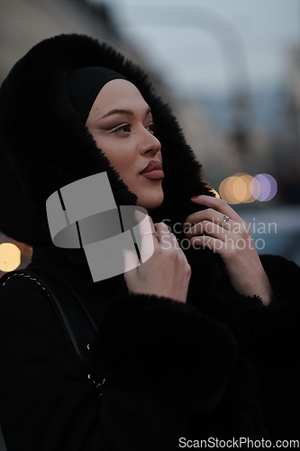 Image of Muslim woman walking on an urban city street on a cold winter night wearing hijab