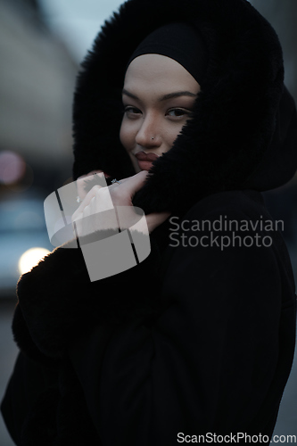 Image of Muslim woman walking on an urban city street on a cold winter night wearing hijab