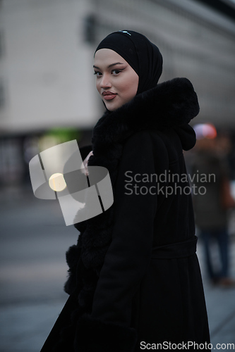 Image of Muslim woman walking on an urban city street on a cold winter night wearing hijab