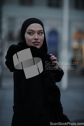 Image of Muslim woman walking on an urban city street on a cold winter night wearing hijab