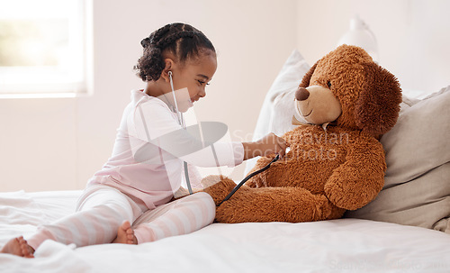 Image of Girl, teddy bear and stethoscope in hospital game in medical, healthcare and wellness bedroom. Happy smile, curious orphan child or fun patient in medicine play activity in pediatric community center