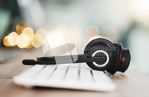 Image of Call center headphones, computer keyboard and telemarketing background in office for contact us, video call and virtual online consulting. Zoom of customer support help desk, technology and connectio