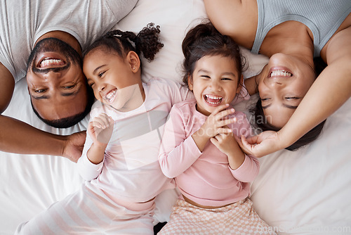 Image of Happy family, love and morning tickling with parents and children lying and playing in bedroom for fun together at home from above. Laughing and man and woman spending time with playful kids to bond