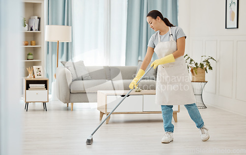 Image of Woman working in a cleaning service mopping the living room floor of a modern home or apartment. Asian cleaner or housewife doing her job or housework to spring clean house for good hygiene lifestyle