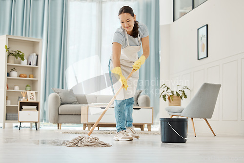 Image of Woman cleaning the floor with a mop in the living room in home with a smile. Happy asian cleaner doing housework or job in a clean lounge, hotel room or house while smiling and alone spring cleaning