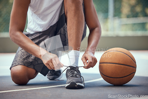 Image of Shoes, basketball and sports with a man basket ball player tying his laces on a court before a game or match. Workout, fitness and exercise with a male athlete outside for health, wellness and cardio