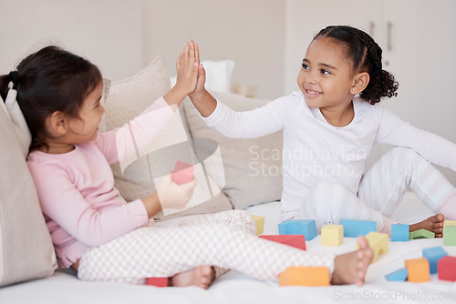 Image of High five, children and fun playing with learning blocks and celebrating achievement or development with colorful toys at home, Adoption and interracial girls, friends or sisters bonding and support