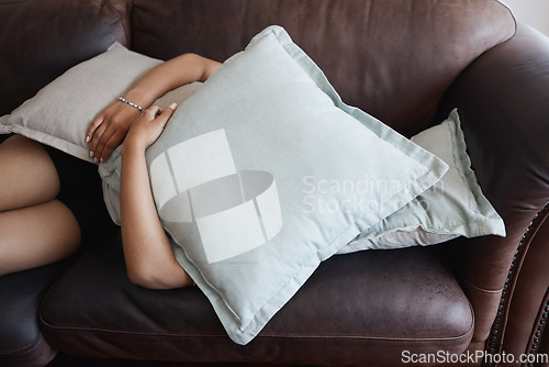 Image of Tired, depressed girl sleeping under pillow on sofa in the living room. Woman hide feeling sad or anxiety and problem with depression, mental health and fatigue or fear on couch in the lounge