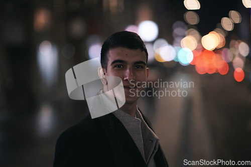 Image of Smiling Meedle Eastern man walking down street near modern office building,