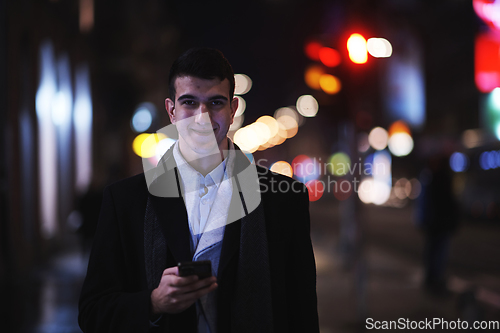 Image of Smiling Meedle Eastern man walking down street near modern office building,