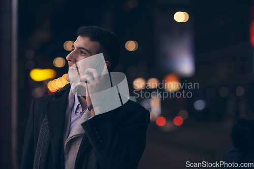 Image of Smiling Meedle Eastern man walking down street near modern office building,