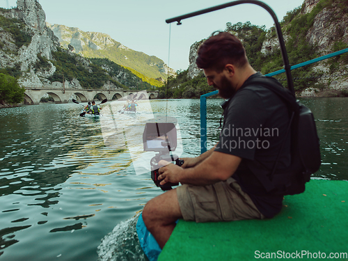 Image of A videographer recording a group of friends kayaking together and exploring river canyons