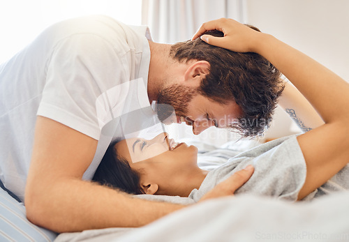 Image of Couple, love and happy with a man and woman in bed in the bedroom of their home together with a smile. Romance, dating and affection with a young male and female bonding and being intimate in a house