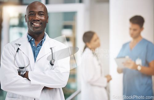 Image of Doctor, healthcare and medicine with a man surgeon standing arms crossed in the hospital with his team in the background. Trust, insurance and care with a male health professional working in a clinic