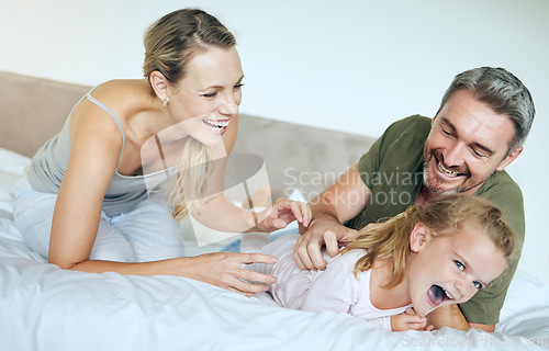 Image of Happy family, bed and fun family playing and laughing while relaxing with little girl in a bedroom. Happy, playful and loving parents being silly with excited child, enjoying free time in their home