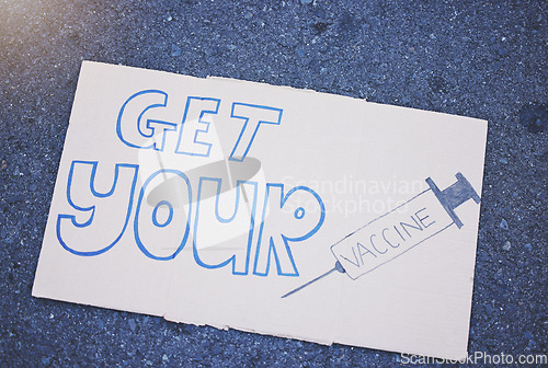 Image of Covid, vaccine and poster with a sign on the ground outside during the corona virus pandemic. Propaganda, motivation and advertising with writing on a board for vaccination, healthcare and medicine