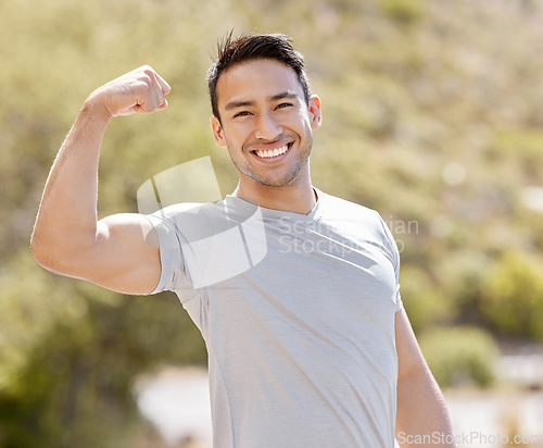 Image of Fitness, nature and a man flexing biceps with a smile while training in outdoor park. Power, flex and stretch before workout or run. Wellness, sports and health, a runner ready for running exercise