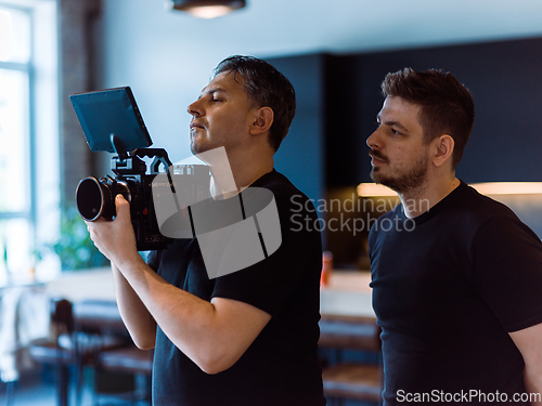 Image of Director of photography with a camera in his hands on the set. Professional videographer at work on filming a movie, commercial or TV series. Filming process indoors, studio