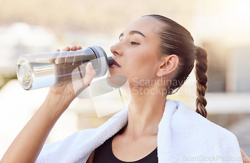 Image of Fitness, exercise and drinking water with woman after workout training with towel around her neck for health, wellness and cardio. Sports, running and motivation with thirsty girl and bottle