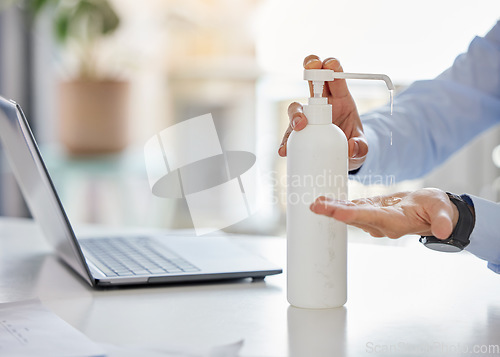 Image of Covid, compliance and hand sanitizer with man cleaning hands before working on a laptop in a corporate office. Health, care and corona rules with professional entrepreneur disinfect workspace desk