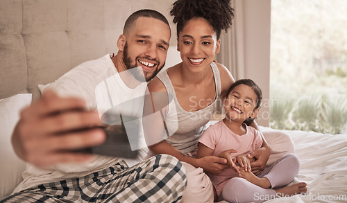 Image of Phone selfie of a relax happy family in bed, bond and enjoy quality time together in home bedroom. Love, morning and happiness for fun couple in pajamas bonding with adopted youth child, kid or girl