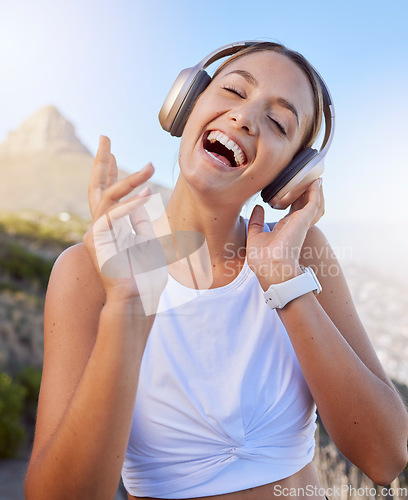 Image of Fitness, headphones and woman outdoor listening to music for wellness podcast while training or doing workout exercise on blue sky and lens flare. Young person with 5g audio for exercise on mountain