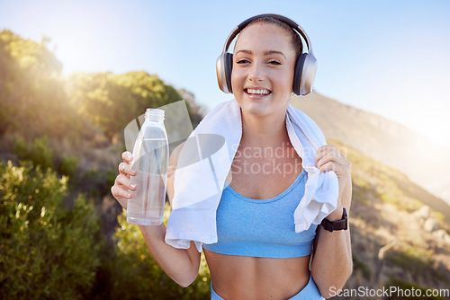 Image of Headphones, nature workout and music streaming of a happy woman after exercise by mountains. Fitness, health and sport person after training drinking water with smile feeling free with happiness