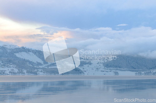 Image of Serene Winter Sunset Over a Snow-Covered Fjord With Fog Rising