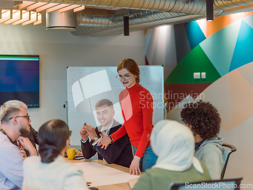 Image of A diverse team of business experts in a modern glass office, attentively listening to a colleague's presentation, fostering collaboration and innovation