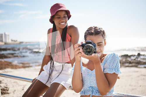 Image of Summer, beach and photographer with camera, young girl taking a photograph. Friends, fun and happy teenagers on holiday by the sea with a scenic ocean view. Portrait of girls, photography and nature