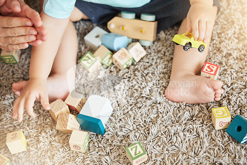 Image of Closeup of baby learning with toys, block puzzle and train to help hand eye coordination on floor in home. Young child learn with education games on carpet, for cognitive development and fun in house