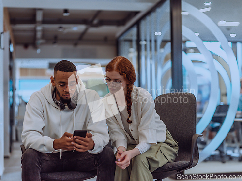 Image of In a modern office African American young businessman and his businesswoman colleague, with her striking orange hair, engage in collaborative problem-solving sessions