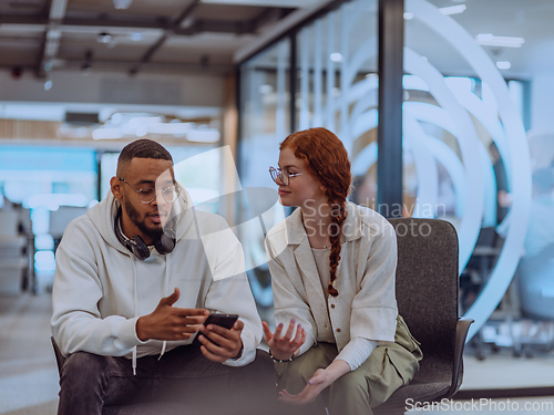 Image of In a modern office African American young businessman and his businesswoman colleague, with her striking orange hair, engage in collaborative problem-solving sessions