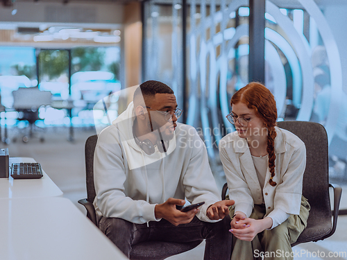 Image of In a modern office African American young businessman and his businesswoman colleague, with her striking orange hair, engage in collaborative problem-solving sessions