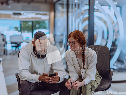 Image of In a modern office African American young businessman and his businesswoman colleague, with her striking orange hair, engage in collaborative problem-solving sessions